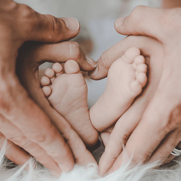Photo de mains qui font un coeur avec des pieds de bébé au milieu
