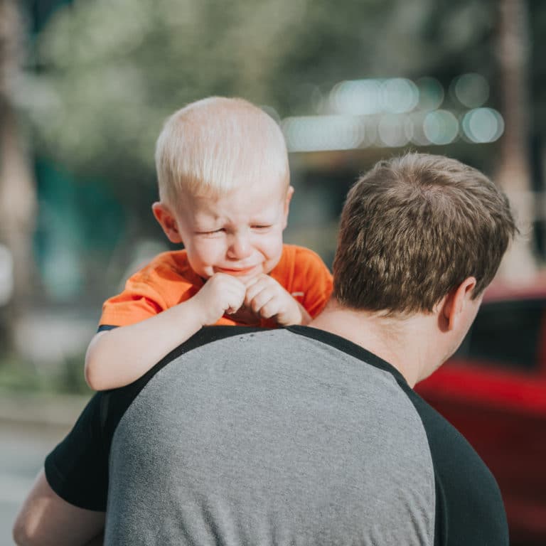 Photo d'un bébé qui pleure dans les bras de son père