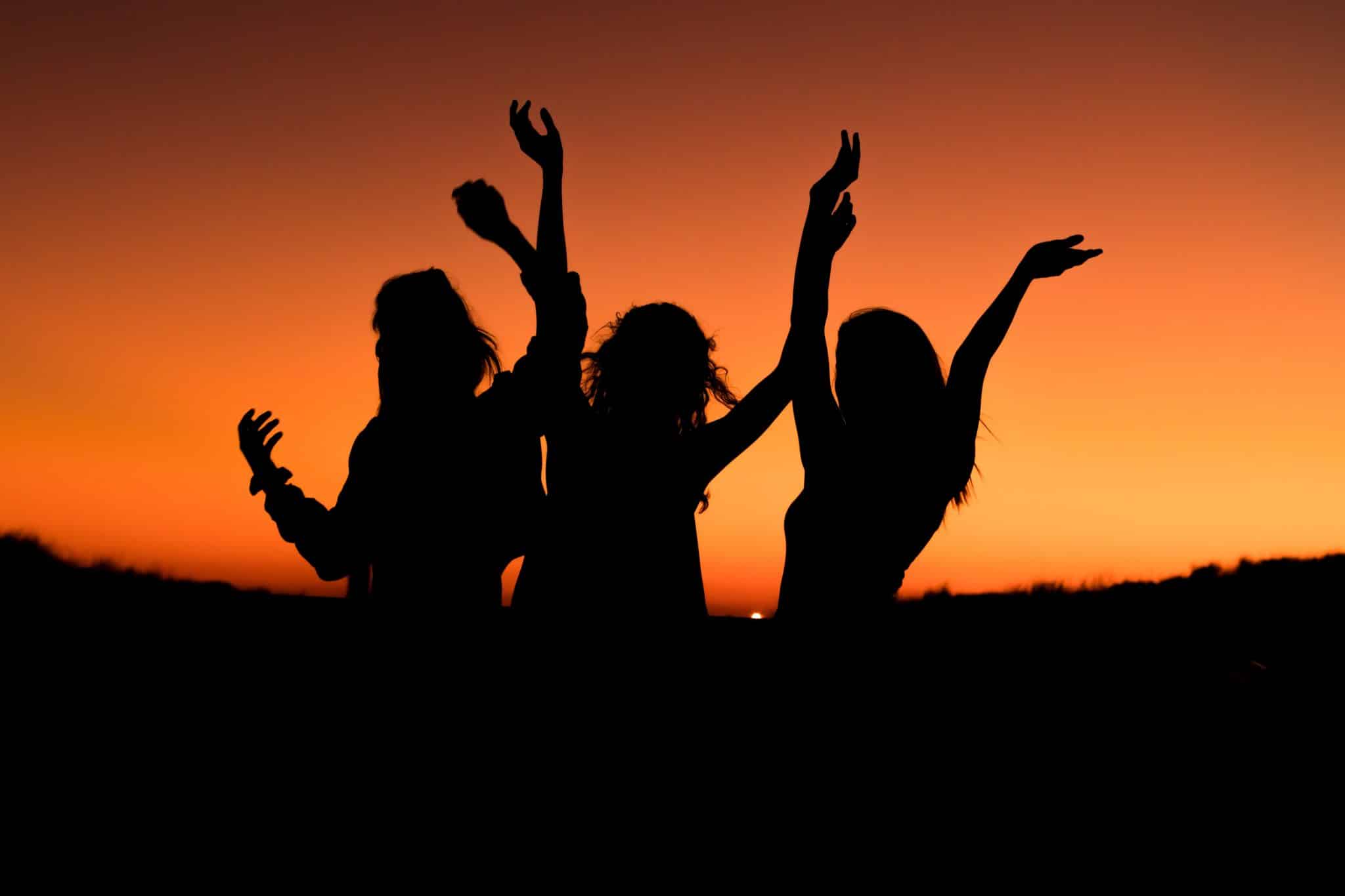 Photo de l'ombre de trois adolescents qui dansent au couché du soleil