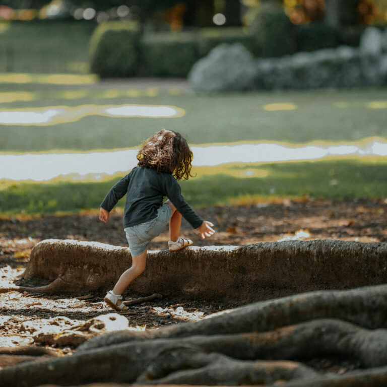 Photo d'un petit enfant qui monte sur un tronc d'arbre devant une rivière